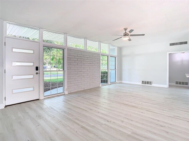 empty room featuring light hardwood / wood-style floors, a wall of windows, and ceiling fan