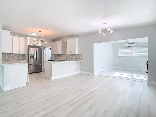 kitchen featuring light countertops, light wood-style floors, open floor plan, a peninsula, and stainless steel fridge with ice dispenser