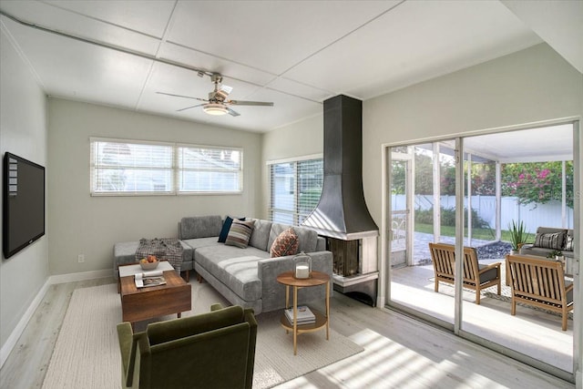 living room with light hardwood / wood-style floors, a water view, a wealth of natural light, and ceiling fan