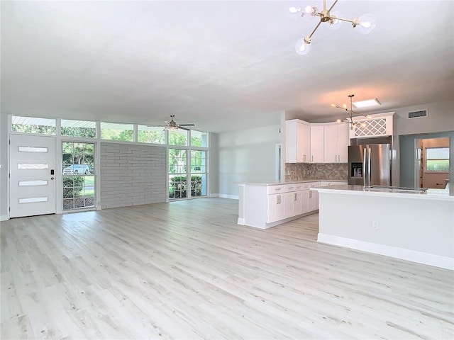 kitchen featuring light hardwood / wood-style flooring, white cabinets, backsplash, expansive windows, and stainless steel fridge with ice dispenser