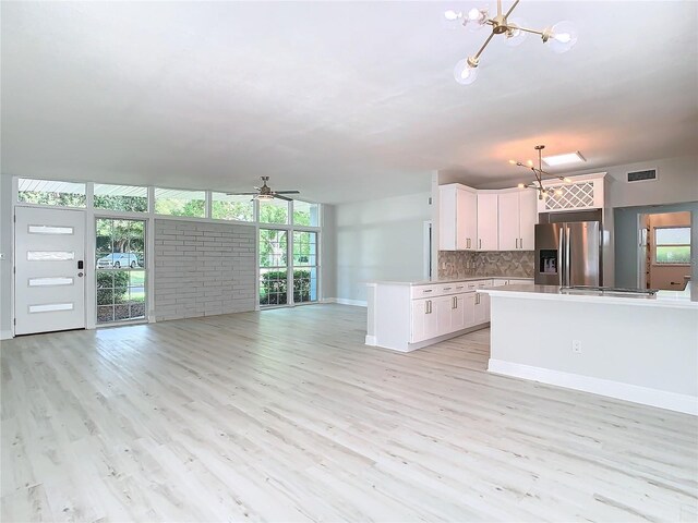 kitchen with floor to ceiling windows, stainless steel refrigerator with ice dispenser, backsplash, open floor plan, and white cabinetry