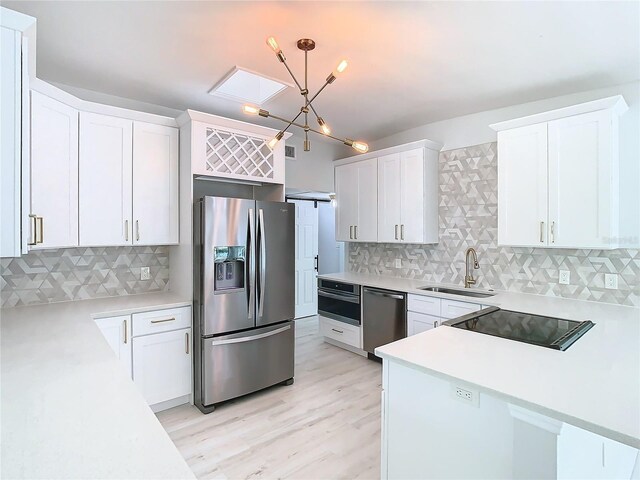 kitchen with decorative backsplash, pendant lighting, sink, appliances with stainless steel finishes, and light hardwood / wood-style flooring