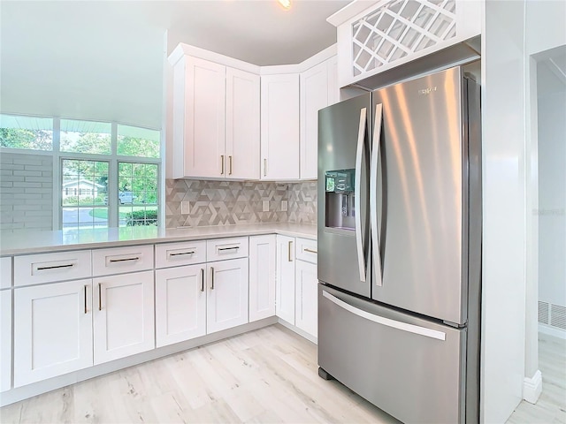 kitchen with light hardwood / wood-style floors, white cabinets, stainless steel refrigerator with ice dispenser, and decorative backsplash