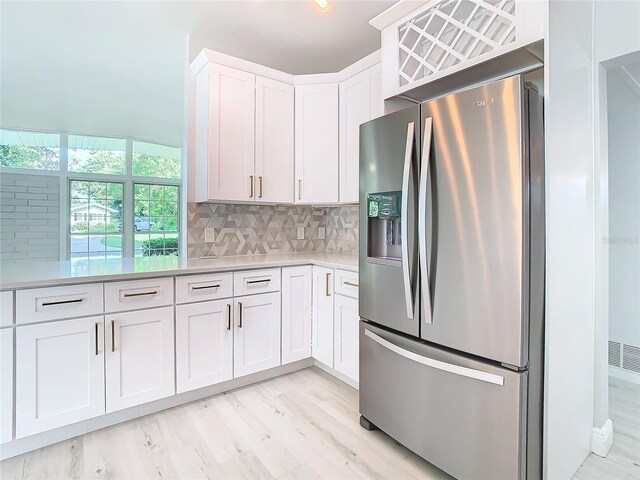 kitchen featuring white cabinetry, light countertops, backsplash, and stainless steel fridge with ice dispenser