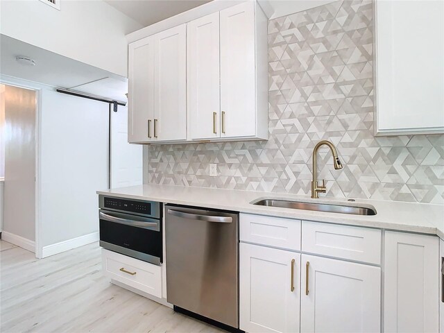 kitchen with white cabinetry, tasteful backsplash, light wood-type flooring, appliances with stainless steel finishes, and sink