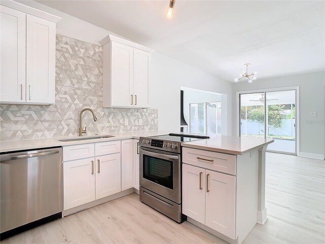 kitchen with decorative backsplash, kitchen peninsula, light hardwood / wood-style flooring, and stainless steel appliances