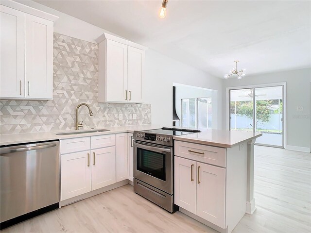 kitchen featuring a peninsula, stainless steel appliances, a sink, and light countertops