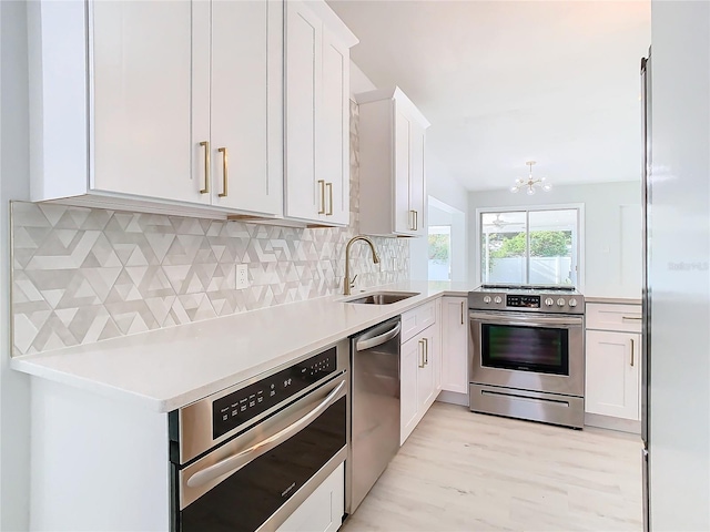 kitchen with light wood-type flooring, white cabinets, backsplash, stainless steel appliances, and sink