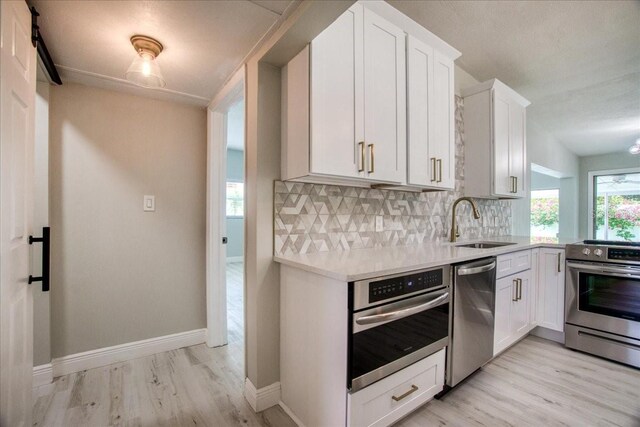 kitchen featuring appliances with stainless steel finishes, light hardwood / wood-style flooring, decorative backsplash, and sink