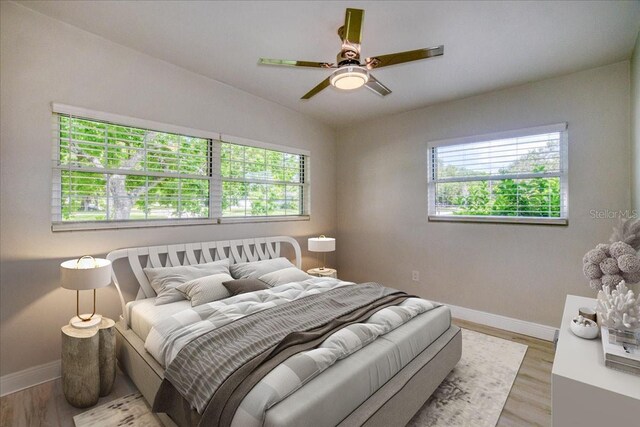 bedroom with ceiling fan, lofted ceiling, and light hardwood / wood-style floors