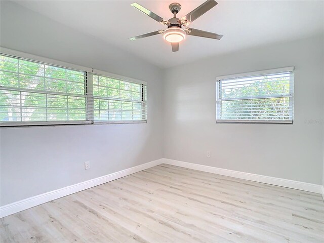 empty room featuring a wealth of natural light, ceiling fan, baseboards, and wood finished floors