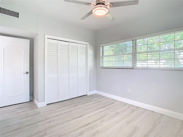 unfurnished bedroom with light wood-type flooring, ceiling fan, and a closet