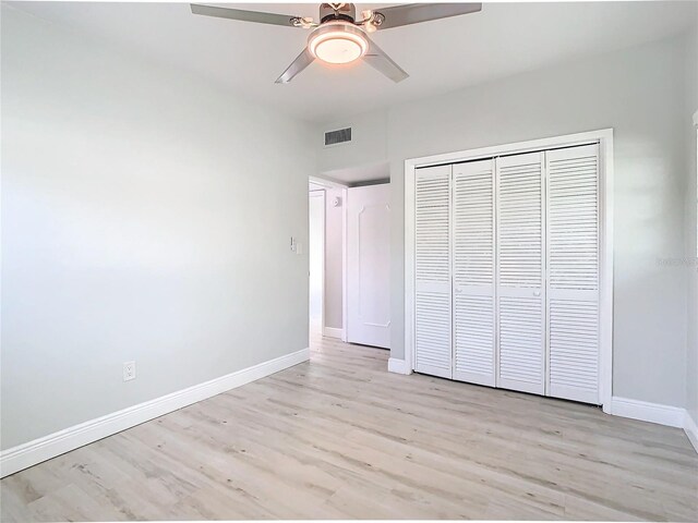 unfurnished bedroom with a closet, visible vents, baseboards, and wood finished floors