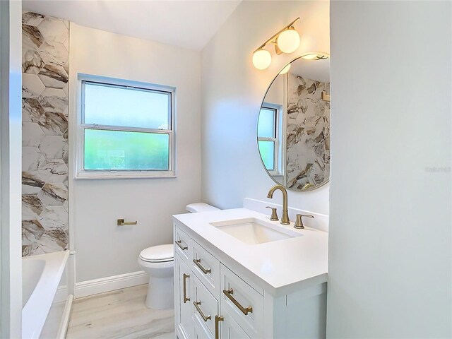 full bathroom featuring hardwood / wood-style flooring, a wealth of natural light, toilet, and vanity