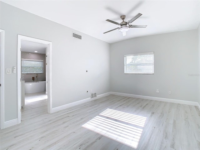 spare room featuring baseboards, a ceiling fan, visible vents, and light wood-style floors