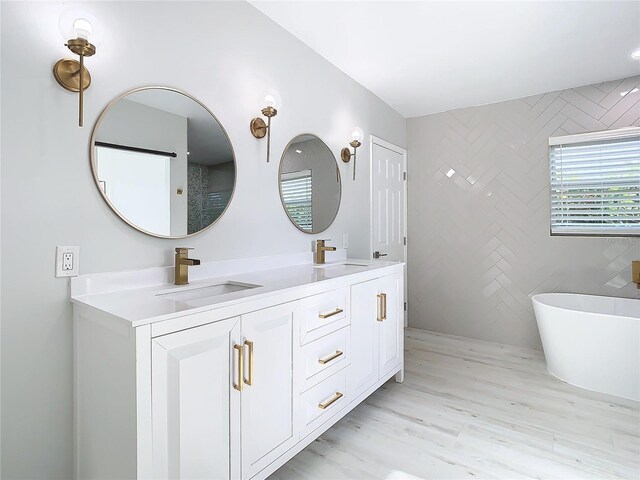 full bath with a freestanding bath, double vanity, a sink, and tile walls