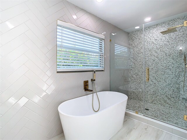 bathroom with tile walls, a freestanding bath, a shower stall, and recessed lighting