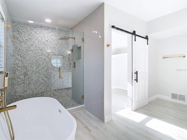 bathroom with recessed lighting, visible vents, a stall shower, wood finished floors, and a freestanding tub