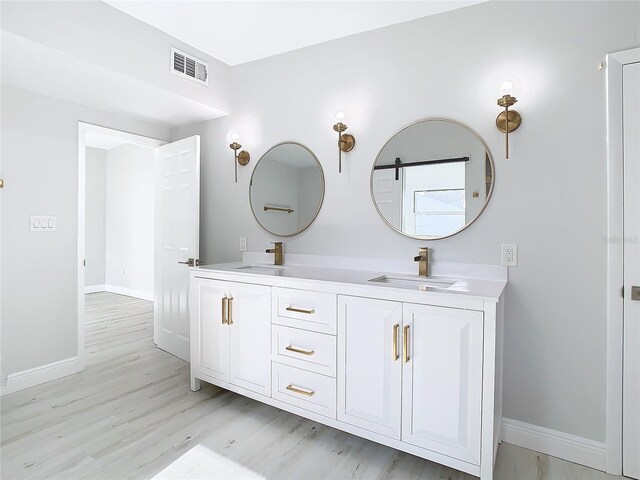 bathroom featuring hardwood / wood-style flooring and dual bowl vanity