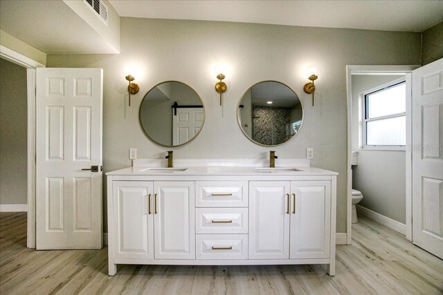 bathroom featuring hardwood / wood-style floors, toilet, and dual bowl vanity