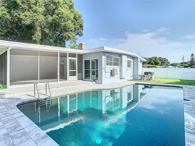 view of swimming pool with cooling unit, fence, a sunroom, a fenced in pool, and a patio area