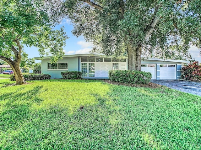 single story home with an attached garage, stucco siding, aphalt driveway, and a front yard