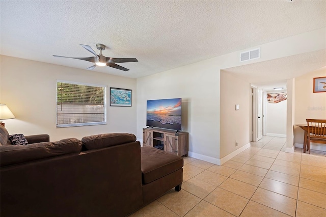 living room featuring ceiling fan, light tile patterned floors, and a textured ceiling