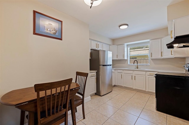 kitchen with light tile patterned floors, wall chimney range hood, white cabinets, stainless steel appliances, and sink