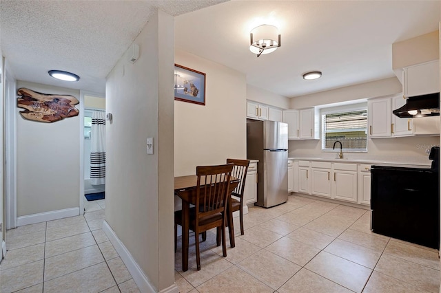 5733 66th Ln N, Saint Petersburg, FL 33709 - kitchen featuring range with electric stovetop, white cabinets, stainless steel fridge, light tile patterned floors, and a textured ceiling