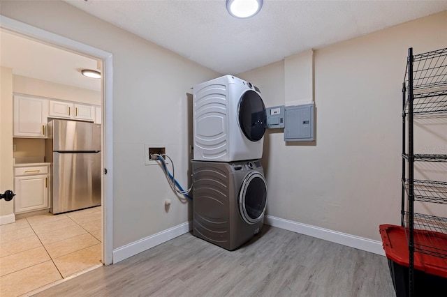 clothes washing area with stacked washer and clothes dryer, electric panel, and light wood-type flooring