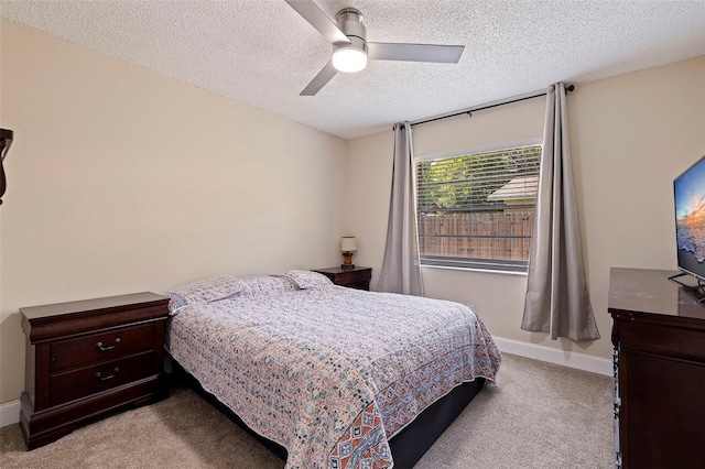 bedroom featuring a textured ceiling, light colored carpet, and ceiling fan