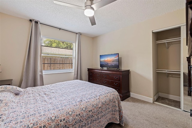 carpeted bedroom with a textured ceiling, ceiling fan, and a closet