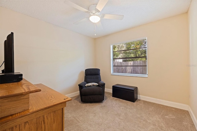 living area featuring light carpet, a textured ceiling, and ceiling fan