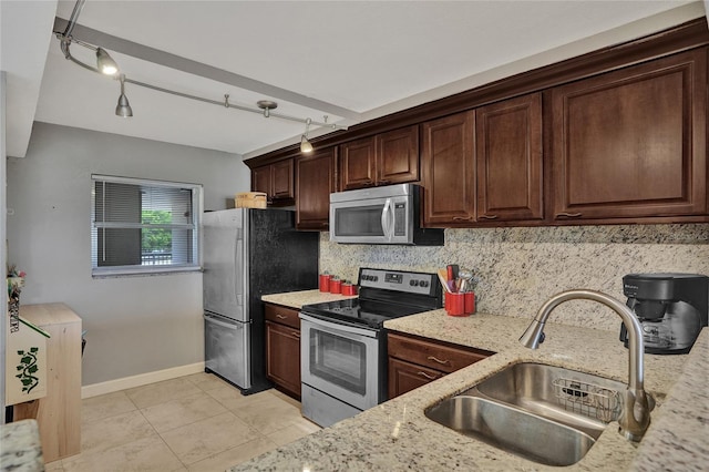 kitchen with light stone counters, light tile patterned flooring, sink, decorative backsplash, and stainless steel appliances