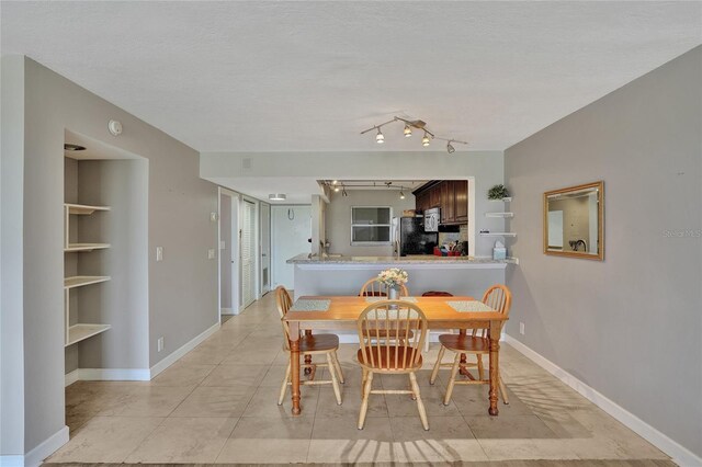 dining area with a textured ceiling and light tile patterned floors