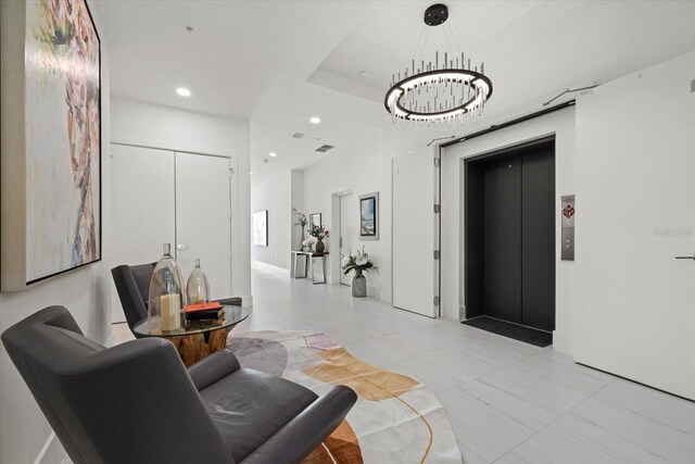 tiled living room with elevator, a notable chandelier, and a tray ceiling