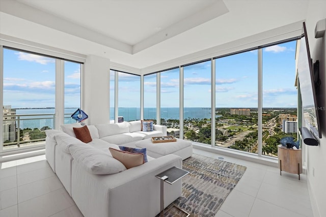 tiled living room featuring a water view and a raised ceiling