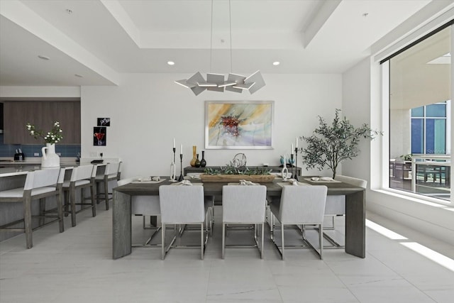 kitchen with light tile patterned flooring, dark brown cabinets, a tray ceiling, and a kitchen bar