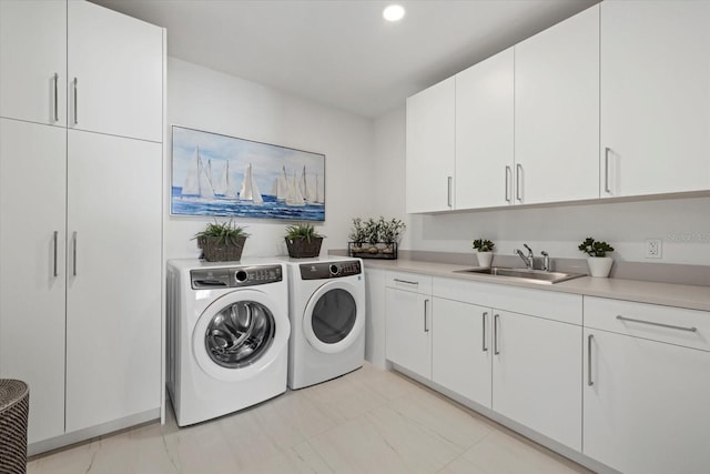 clothes washing area featuring light tile patterned floors, cabinets, washer and dryer, and sink