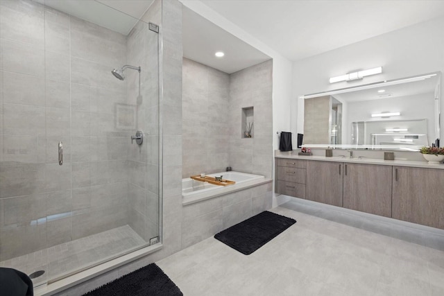 bathroom featuring plus walk in shower, vanity, and tile patterned floors