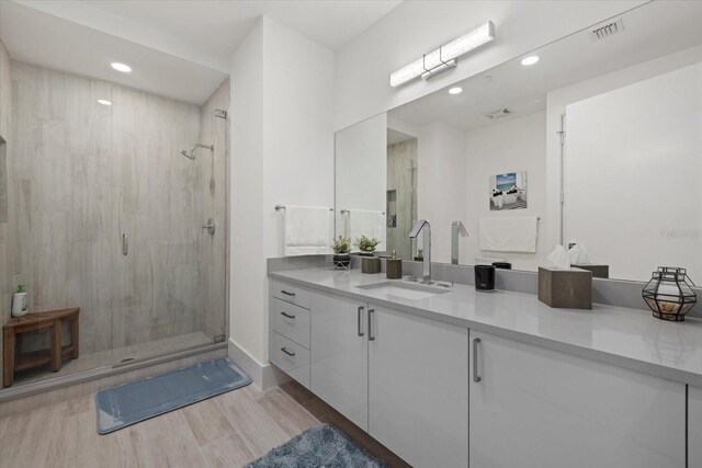 bathroom with a shower with shower door and vanity