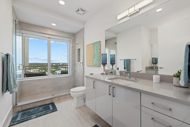 bathroom with a shower with shower door, vanity, tile patterned flooring, and toilet