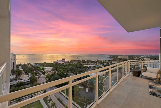 balcony at dusk featuring a water view