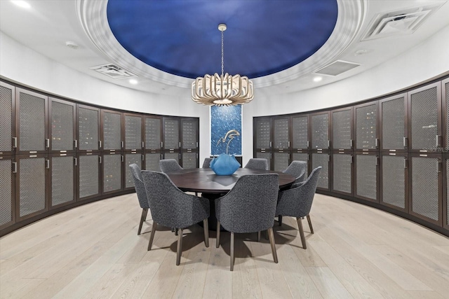 dining space featuring wood-type flooring, an inviting chandelier, and a tray ceiling