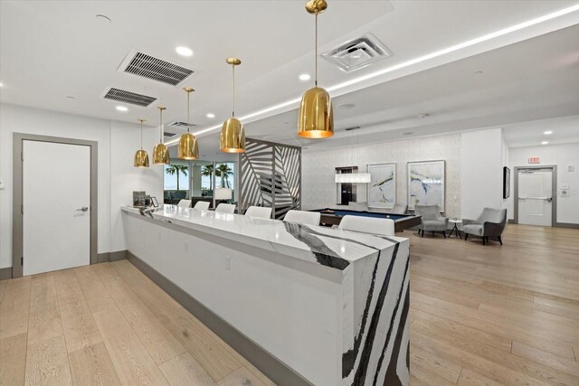 kitchen featuring light hardwood / wood-style flooring, kitchen peninsula, stone countertops, decorative light fixtures, and pool table