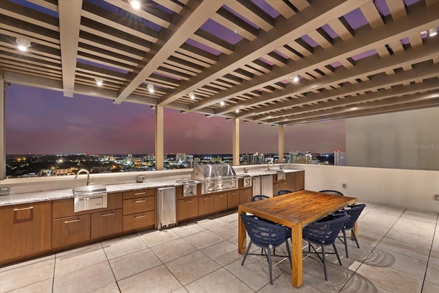 patio terrace at dusk featuring sink, a pergola, exterior kitchen, and a grill