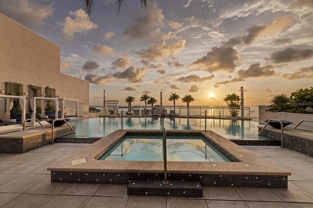 pool at dusk with a community hot tub and a patio area