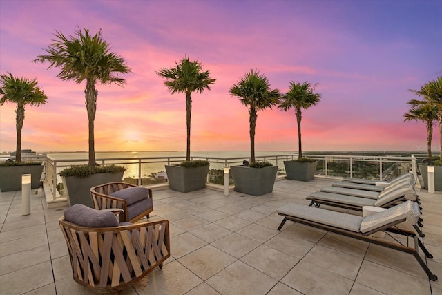 patio terrace at dusk featuring a water view