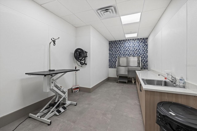 exercise area featuring light tile patterned floors, sink, and a drop ceiling