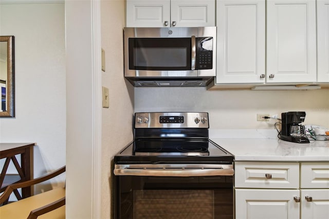 kitchen featuring appliances with stainless steel finishes, light stone countertops, and white cabinets